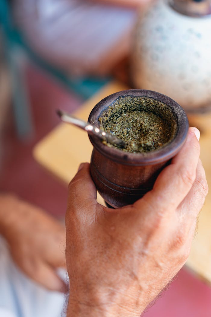 Consultation Booking Close-up of a hand holding a wooden cup of yerba mate, highlighting cultural tradition.